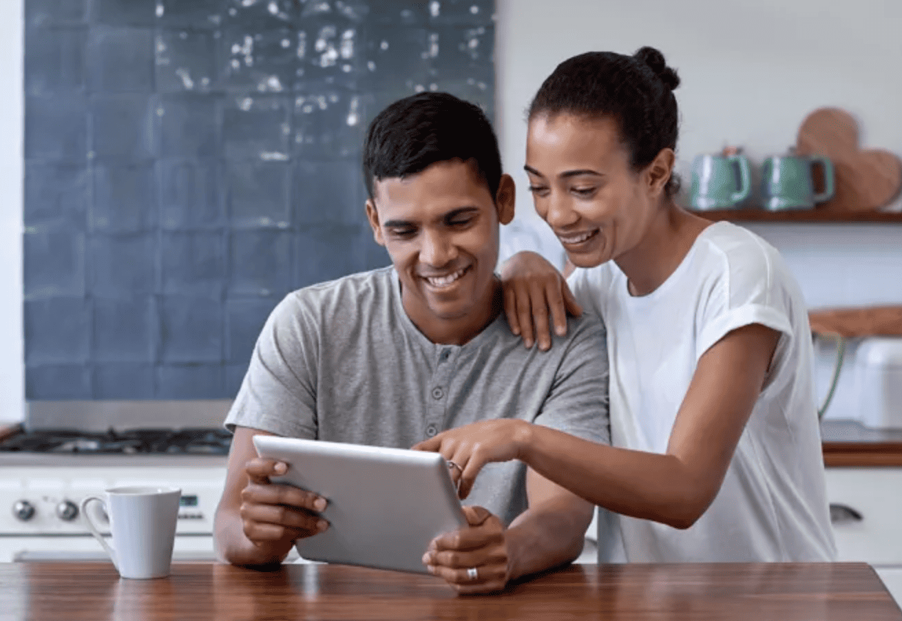 Man in office with coffee, smiling while working at laptop, captures the essence of remote work.